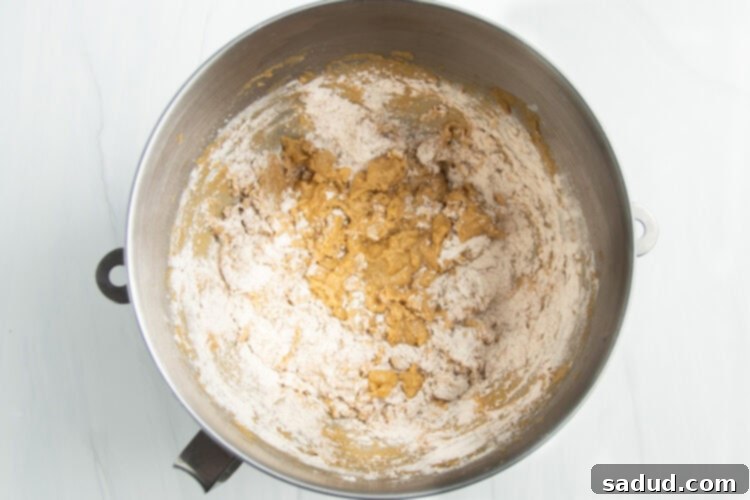 Overhead view of a silver stand mixer bowl with gluten free flour added to creamed butter and sugar.
