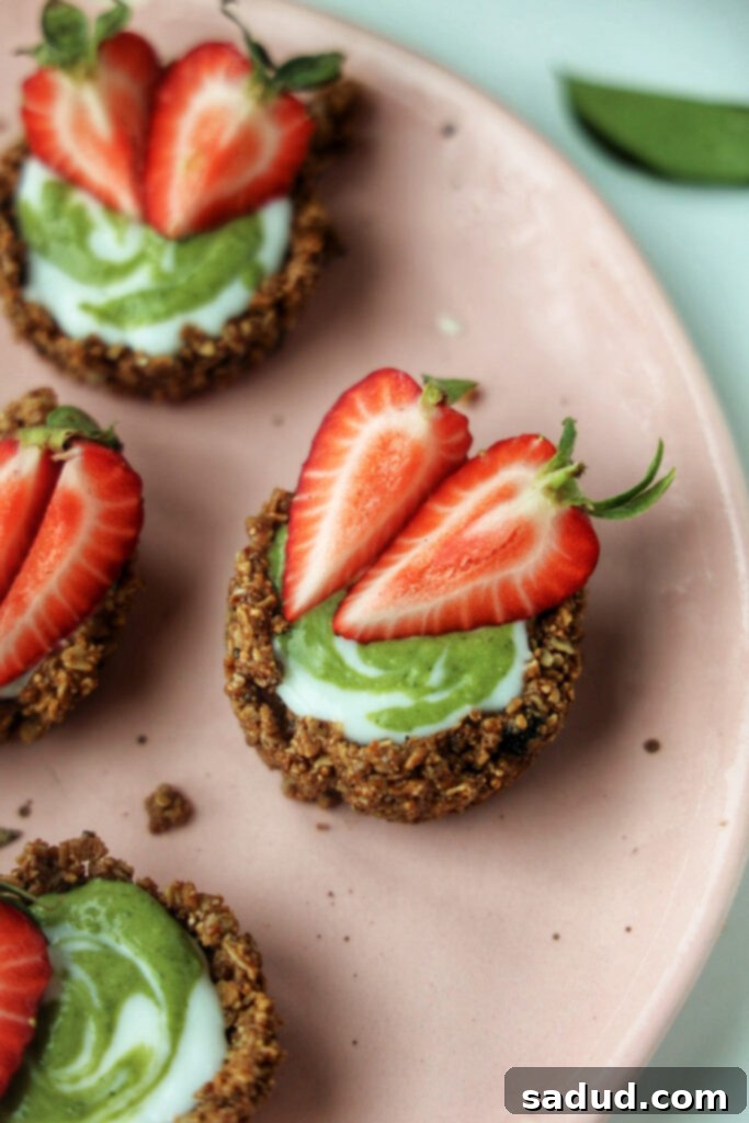 A plate of strawberry matcha granola tarts, beautifully arranged with fresh strawberries.