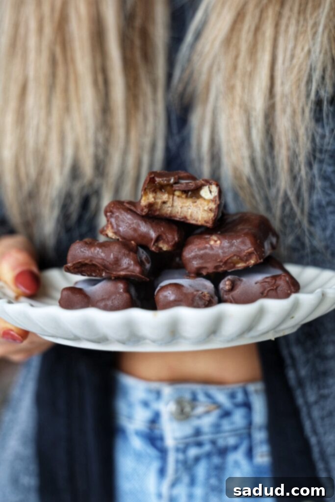 A plate of healthier pecan snickers bars, showcasing their chocolate coating and caramel-pecan filling.