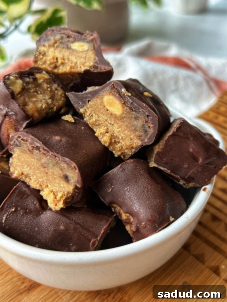 Homemade Vegan Snickers Protein Bars - a close-up of the finished healthy treat, showcasing layers of nougat, caramel, peanuts, and chocolate coating.