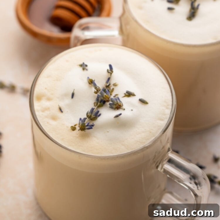 A London fog latte in a clear glass mug sitting on a table, garnished with a star anise.