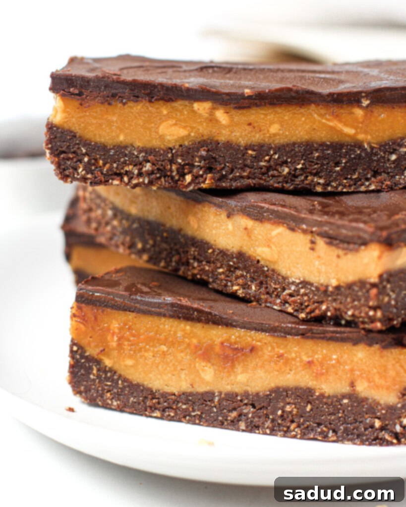 A beautifully arranged stack of healthy no-bake peanut butter bars, showcasing their distinct layers of chocolate base, peanut butter filling, and chocolate topping.
