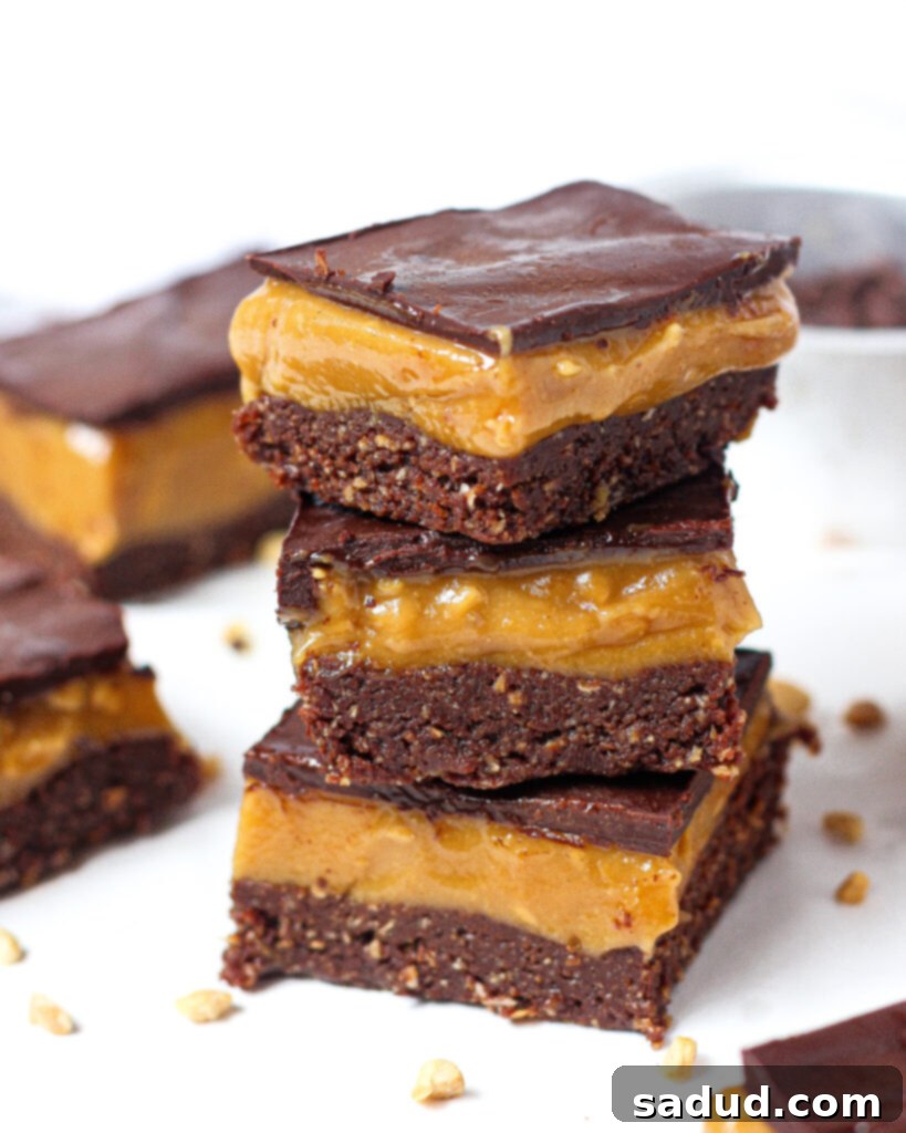 A close-up shot of the healthy no-bake peanut butter bars, showing the smooth, creamy peanut butter layer beneath the glossy chocolate topping, with a hint of the dark base.
