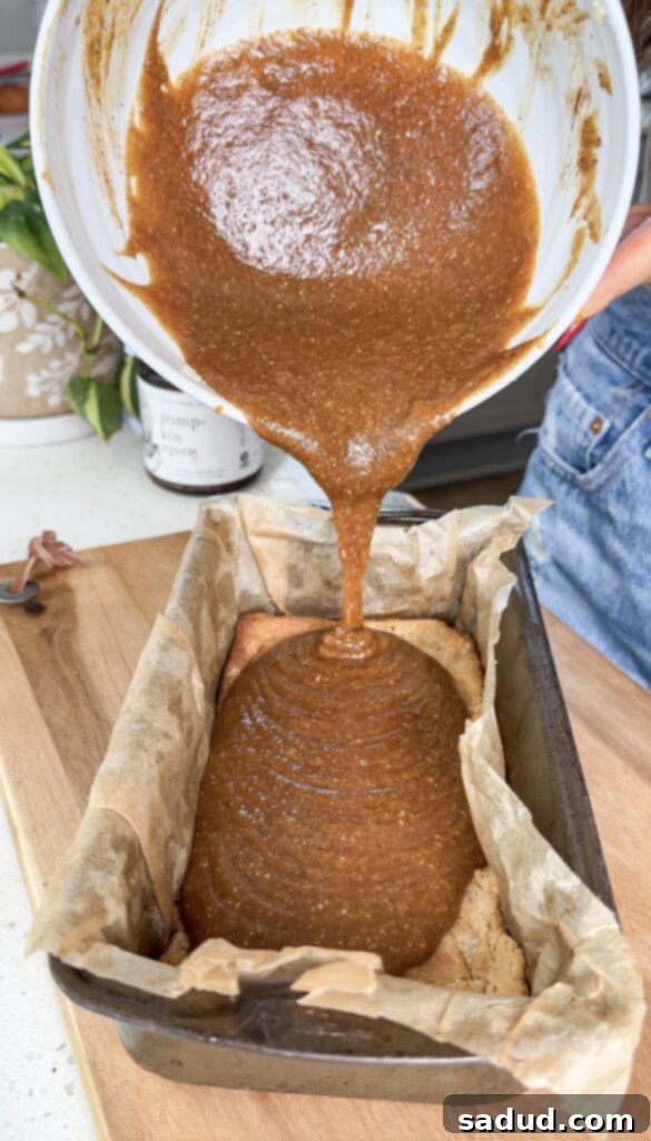 Pouring pumpkin caramel filling over the shortbread cookie base for vegan Twix bars.