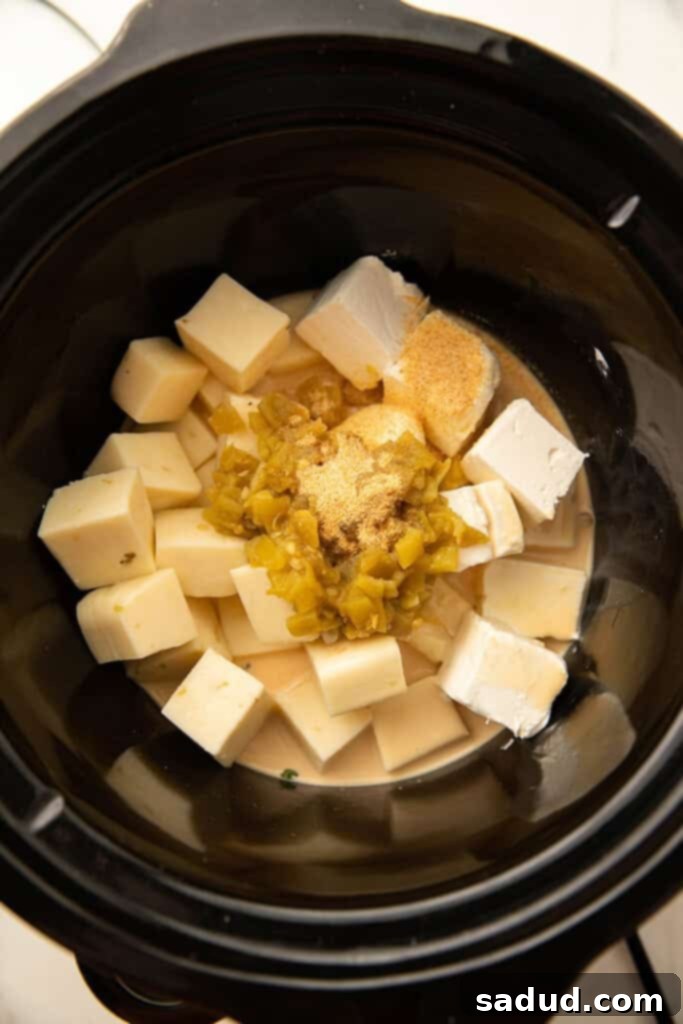 Effortless Slow Cooker Queso 3 Cubed Monterey Jack and cream cheese, mixed with diced jalapeños and evaporated milk, ready for slow cooking.