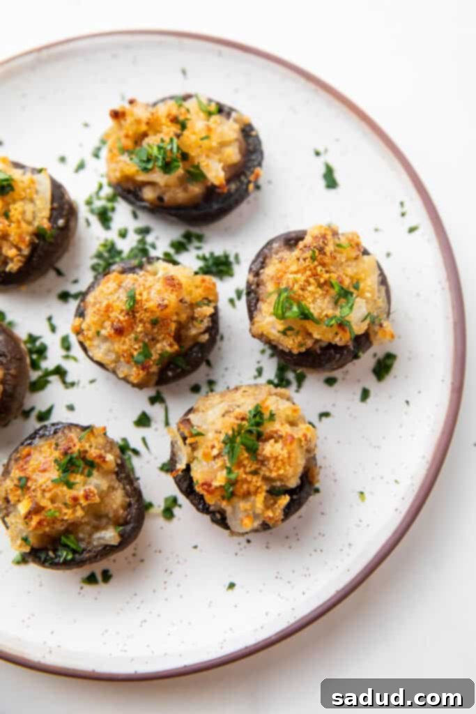 Platter of freshly baked vegetarian stuffed mushrooms on a white serving plate, ready to be enjoyed.