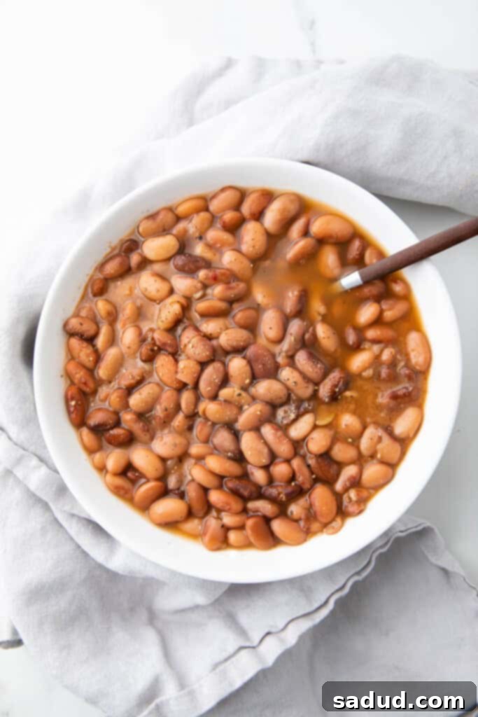 White bowl of slow cooker pinto beans with a spoon