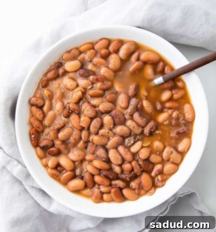White bowl of slow cooker pinto beans with a spoon