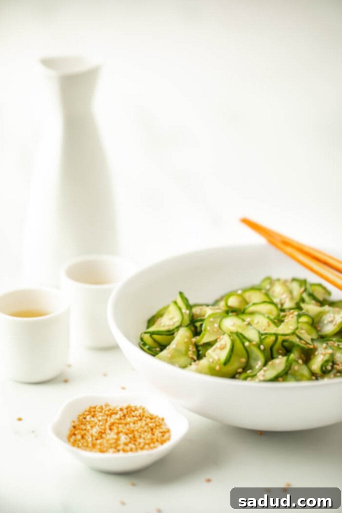 Refreshing Asian Cucumber Salad 4 Simple Asian cucumber salad in a white bowl surrounded by bottles of sake and sesame seeds