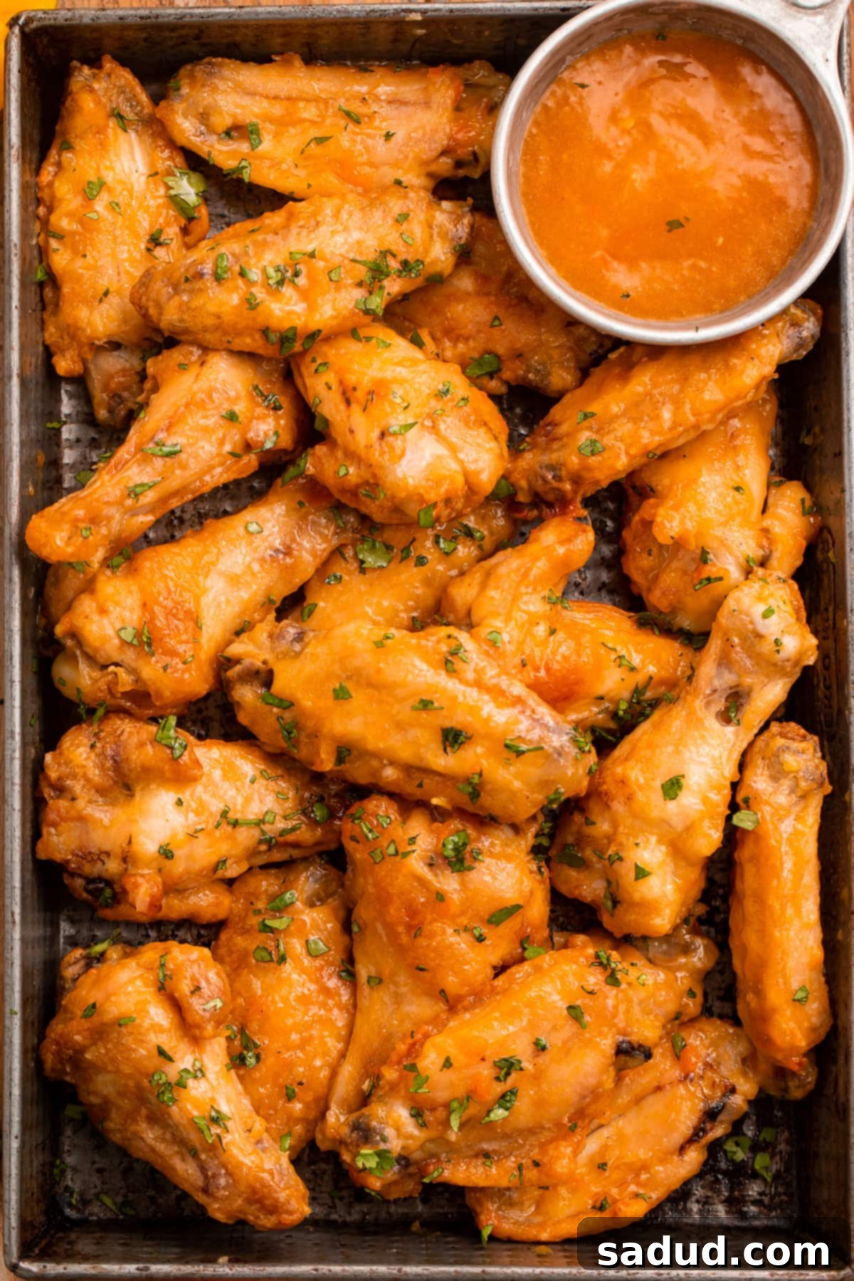Sweet Heat Mango Habanero Wings 3 Overhead view of a pan of juicy chicken wings in an orange mango habanero sauce.