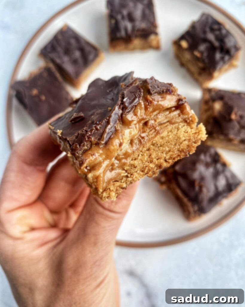 Decadent Samoa Protein Bars 2 An up-close shot of a Samoa cookie protein bar showcasing its distinct layers of cookie base, caramel coconut filling, and chocolate topping.