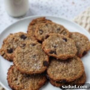 A close-up shot of a single chewy vegan chocolate chip cookie, showcasing its soft interior and melted chocolate chips.