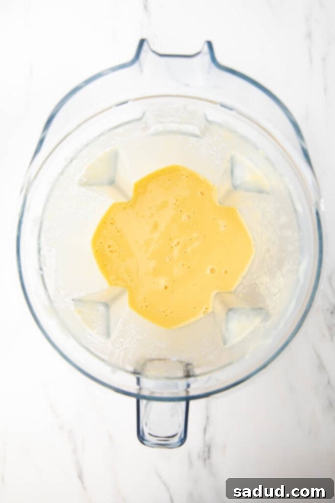 The mango pineapple smoothie freshly blended to a smooth, creamy consistency in the blender jar.