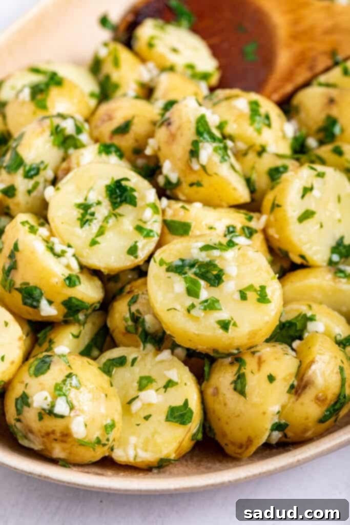 Garlic butter parsley potatoes in a serving dish with a wooden spoon, ready to be enjoyed.