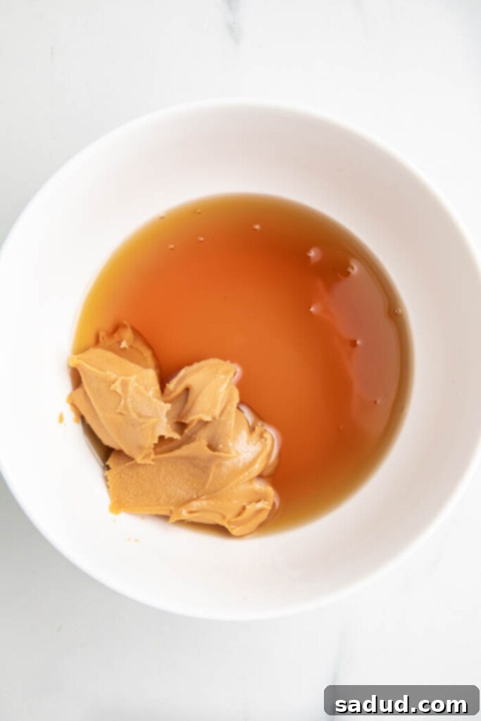 Peanut butter and maple syrup being whisked together in a white bowl