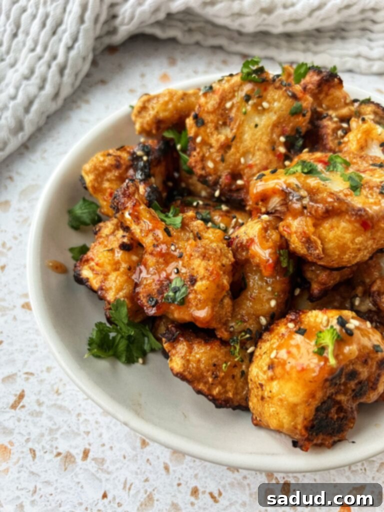 Sweet & Spicy Cauliflower wings (Vegan, gluten free) served in a bowl, garnished with sesame seeds and green onions.