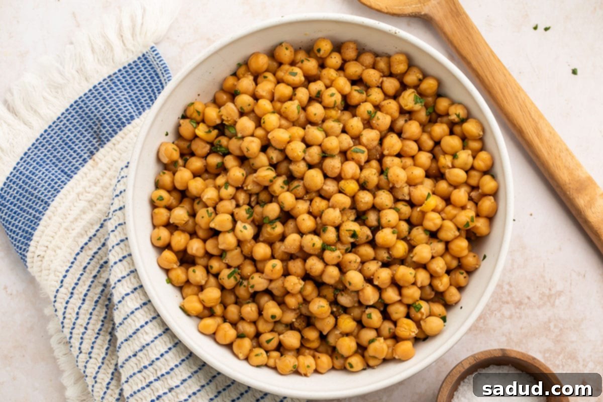 No Soak Instant Pot Chickpeas 3 A large white bowl brimming with freshly prepared, no-soak Instant Pot chickpeas, glistening slightly with broth, indicating their moist and tender texture, ready for immediate use.