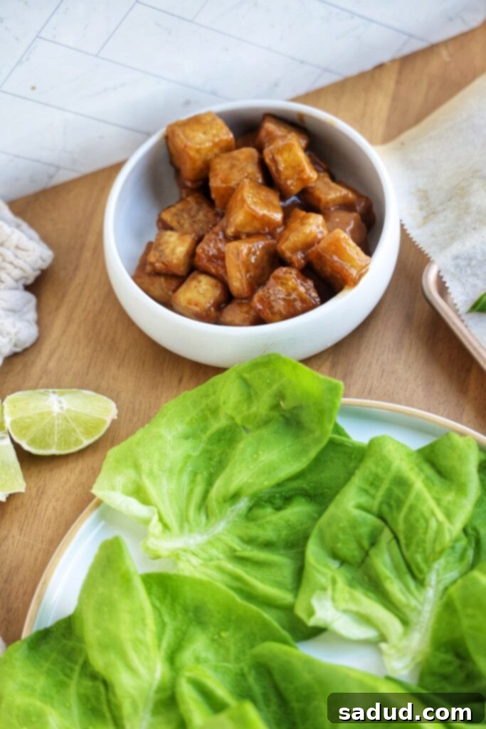 Healthy Orange Glazed Vegan Tofu 3 Close-up of fresh ingredients for sticky orange tofu lettuce cups: pressed tofu, butter lettuce, lime, and orange slices.