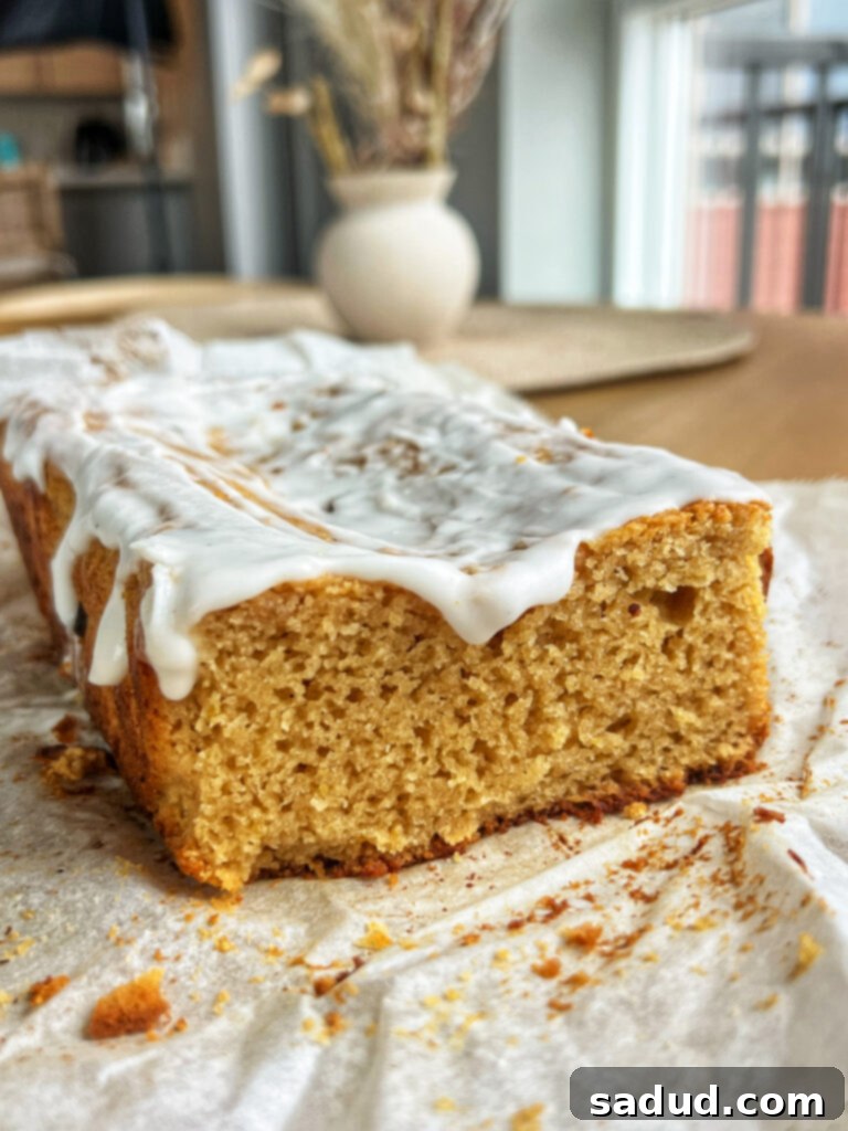 Zesty Lemon Glazed Paleo Gluten-Free Loaf 2 A freshly baked, healthy glazed lemon loaf on a white plate, ready to be served. The bright yellow glaze is drizzled beautifully over the golden brown bread, indicating its delicious lemon flavor and moist texture.
