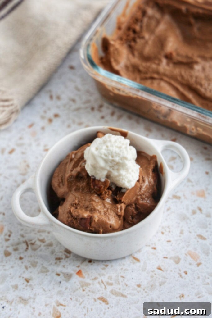 A cup of peanut butter cup nice cream topped with creamy coconut whipped cream.