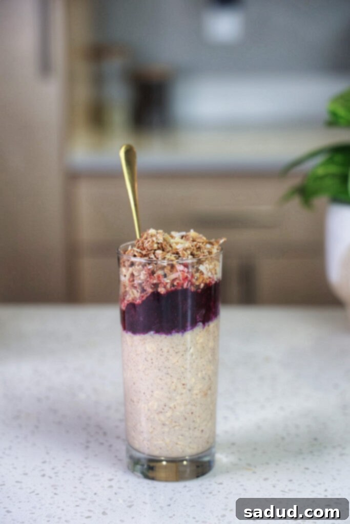 A jar of blueberry crisp overnight oats, topped with fresh berries and a golden-brown crumble.
