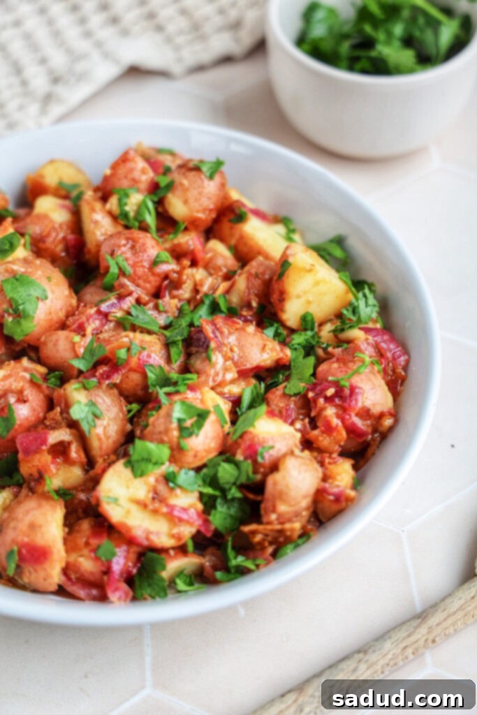 A bowl of german potato salad topped with parsley.