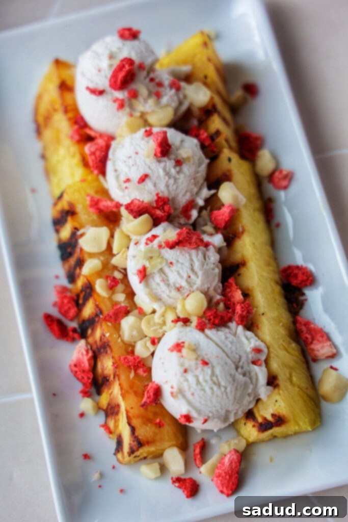 Grilled Pineapple Sundae 2 A beautifully plated grilled pineapple split with creamy vanilla ice cream, macadamia nuts, and freeze-dried strawberries.