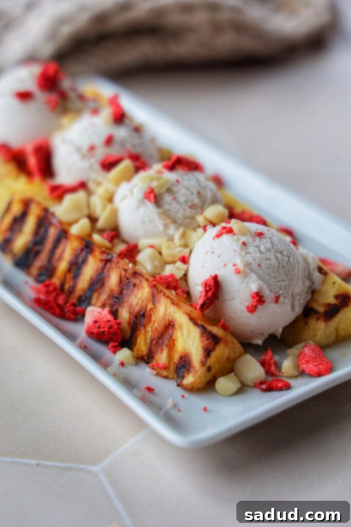 Grilled Pineapple Sundae 4 Grilled pineapple split topped with ice cream and macadamia nuts, ready to be enjoyed.
