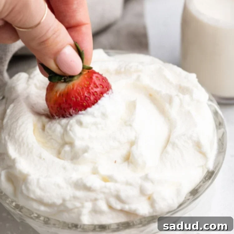 a strawberry being dipped in keto whipped cream
