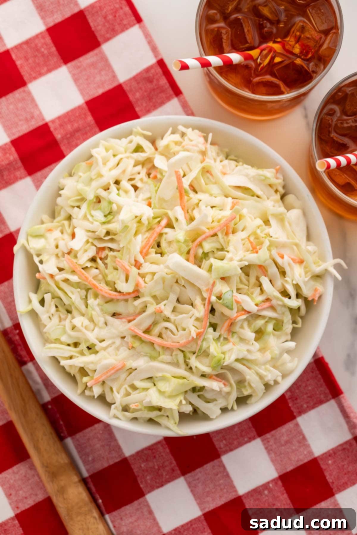 A large bowl of copycat Chick-fil-a coleslaw on a red and white checkerboard tablecloth.