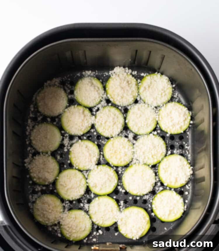 Zucchini chips with parmesan cheese in the air fryer basket, ready to cook