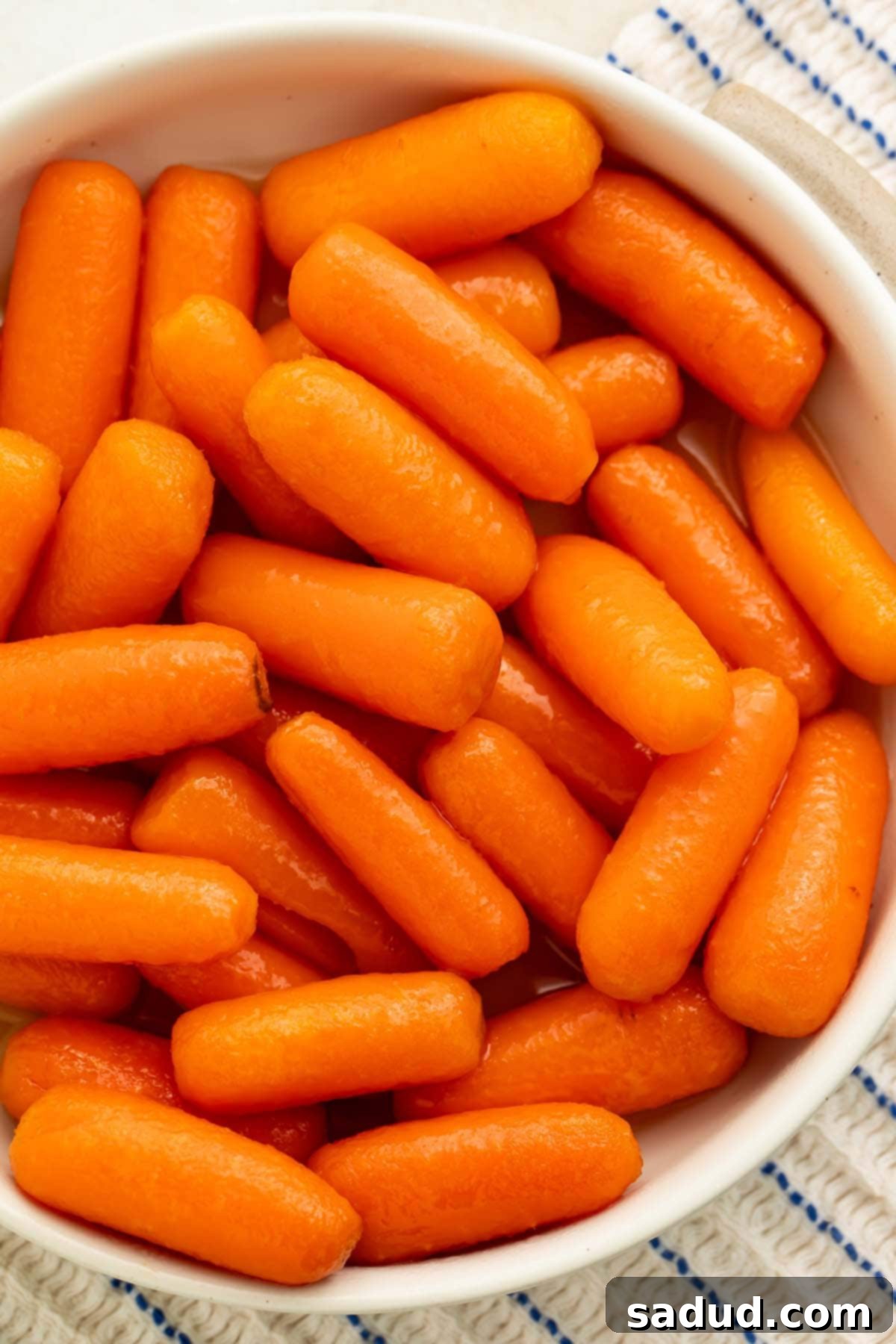 A white bowl holding buttery carrots cooked in the Instant Pot, garnished with fresh herbs.
