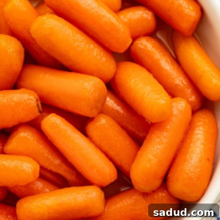 A white bowl holding buttery carrots cooked in the Instant Pot, coated in a maple butter sauce.
