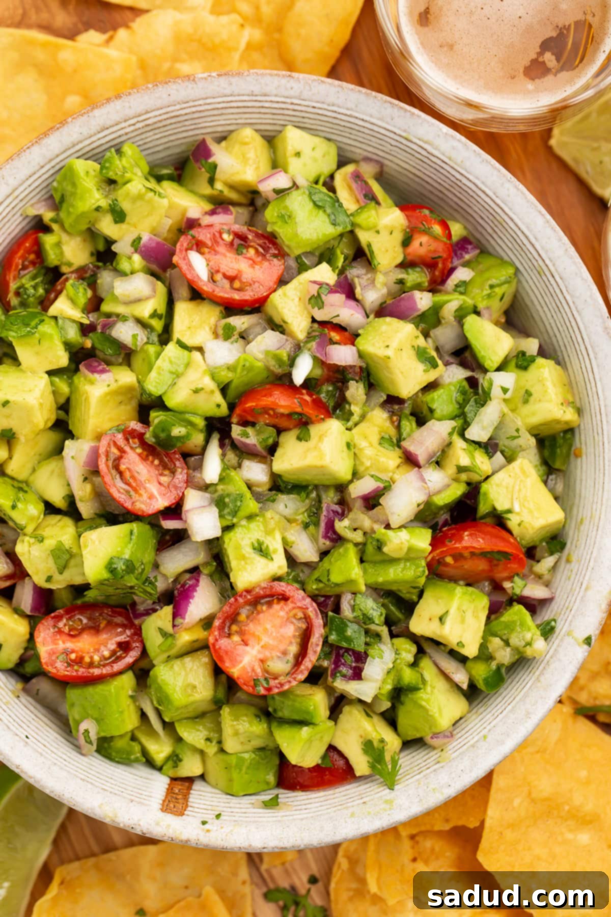 Close-up view of chunky guacamole salad with avocado and cherry tomatoes in a large white bowl.