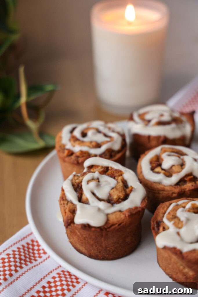 A plate of perfectly glazed gluten-free and paleo apple cinnamon roll muffins, showcasing their gooey centers and fluffy texture, ready to be enjoyed as a fall treat.