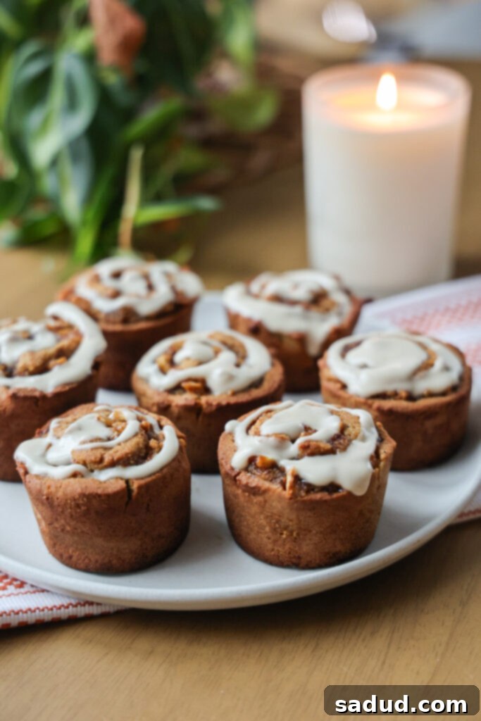 A close-up shot of a single apple cinnamon roll muffin, showing its rich glaze and the intricate cinnamon-apple swirl inside, highlighting its delicious fall appeal.