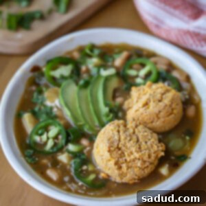 A bowl of vegan white bean chili with cornbread biscuits and fresh cilantro garnish.