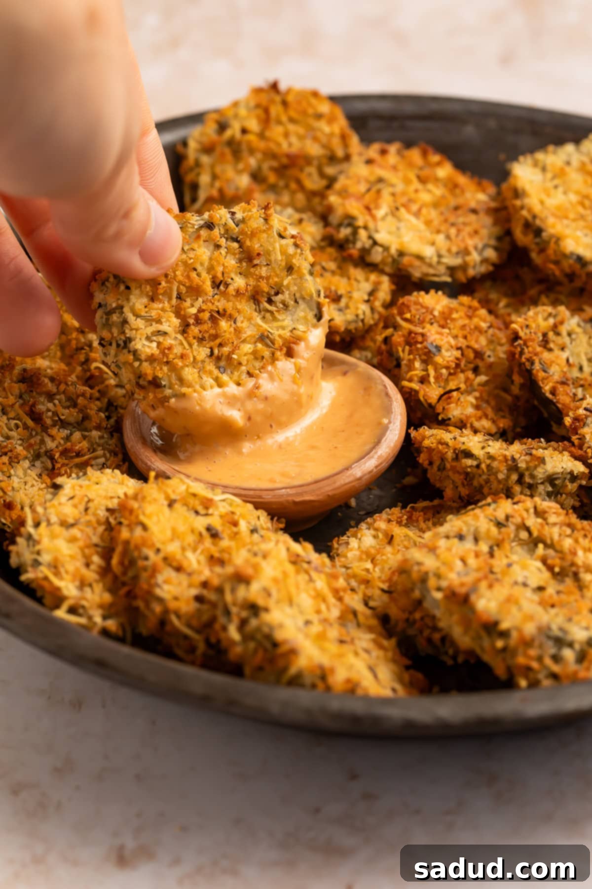 Golden Crisp Air Fryer Pickles 3 Fried pickle being dipped into a creamy, spicy sauce.