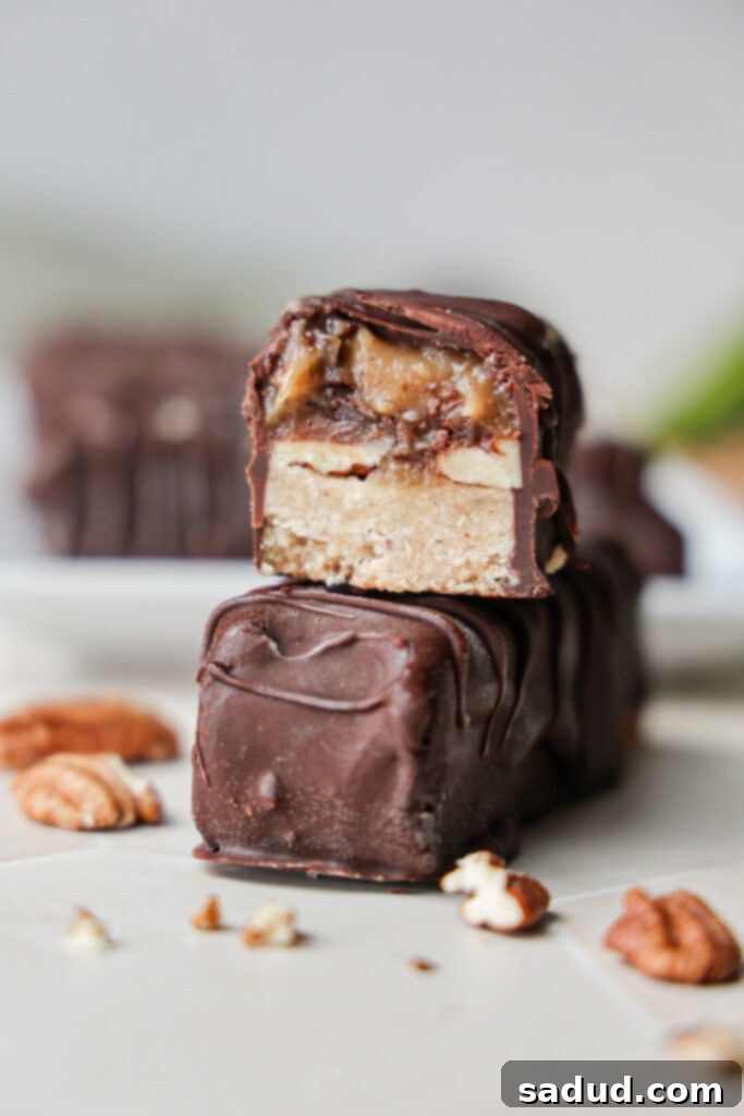 Wholesome Vegan Gluten Free Pecan Twix Bars 2 A stack of pecan twix bars, showcasing the various layers: shortbread, caramel, pecans, and chocolate.