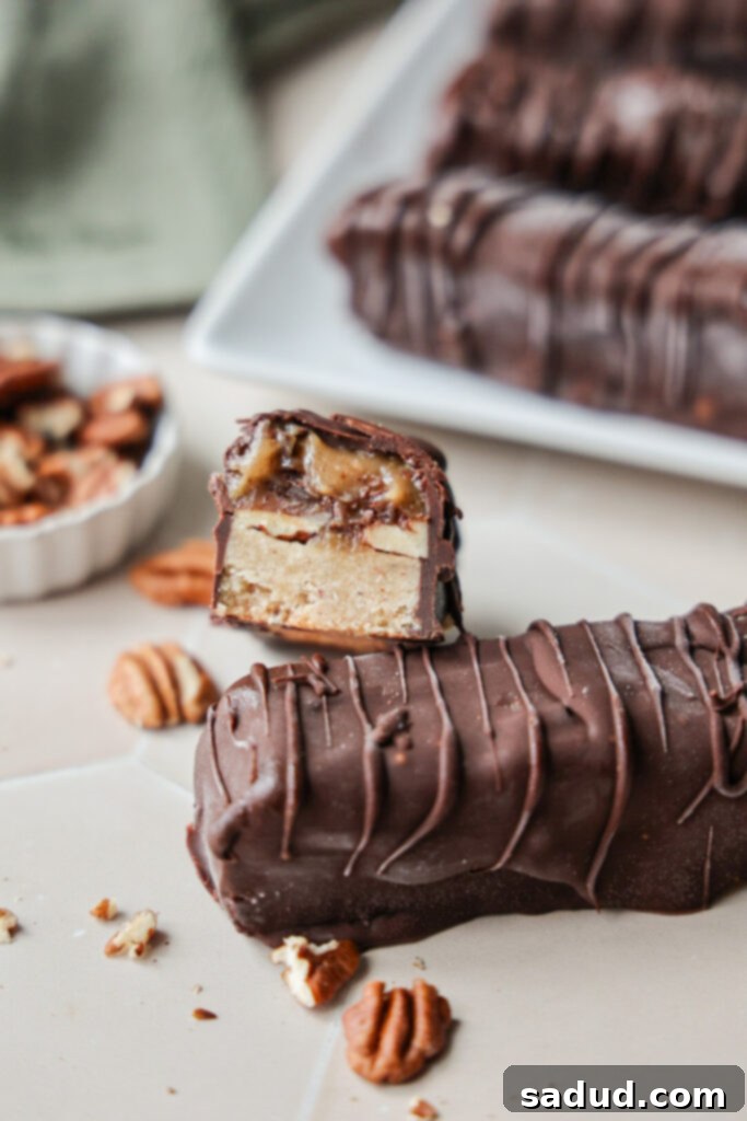 Wholesome Vegan Gluten Free Pecan Twix Bars 3 A pecan twix bar cut open to show the gooey caramel inside, with visible chopped pecans.