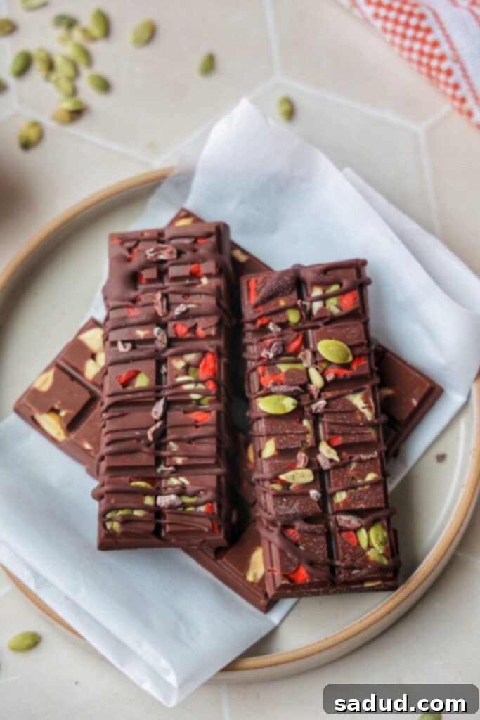 A plate of homemade superfood chocolate bars, showcasing a rich dark chocolate base with colorful mix-ins like goji berries and seeds.