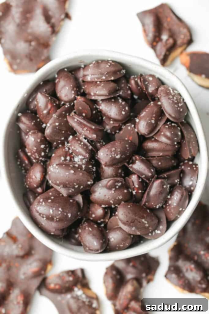 Overhead shot of a bowl brimming with finished chocolate covered almonds, sprinkled with sea salt.