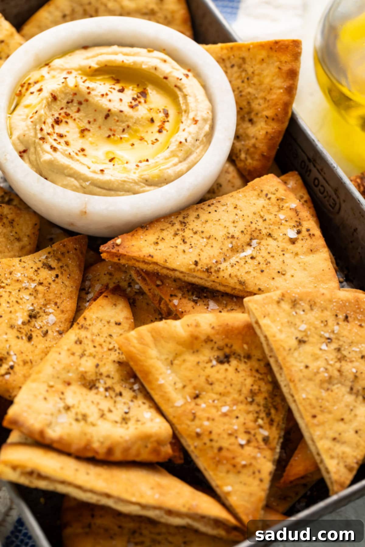 Close-up of homemade pita chips with a small dipping bowl of hummus.