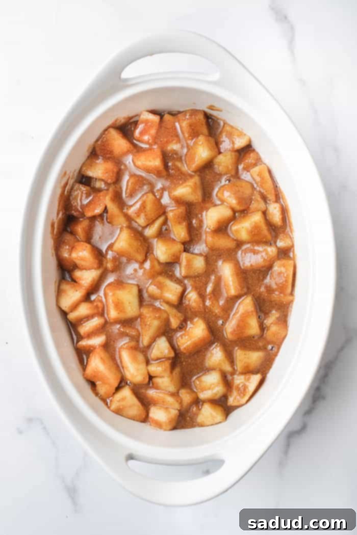 Apple filling spread evenly in a glass baking dish, ready for the topping.