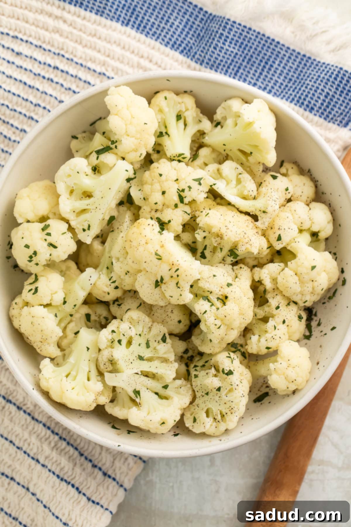 Simple Instant Pot Cauliflower 3 A large white bowl holding Instant Pot Cauliflower seasoned with fresh herbs, ready to be served.
