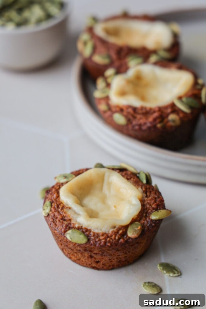 Delicious and healthy pumpkin cream cheese muffin, golden brown with pumpkin seeds on top.