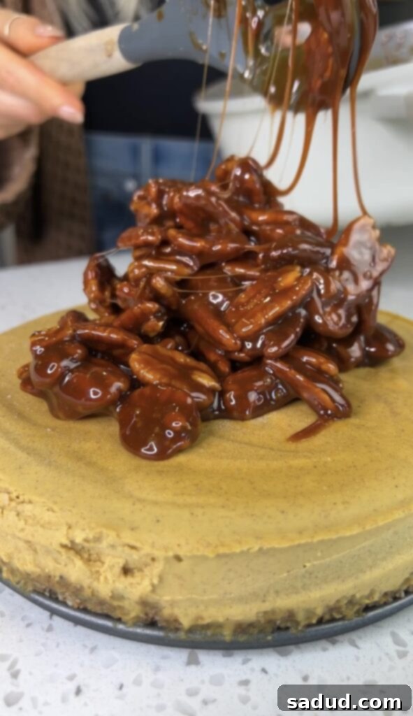Caramel pecan topping being spread on the cheesecake.