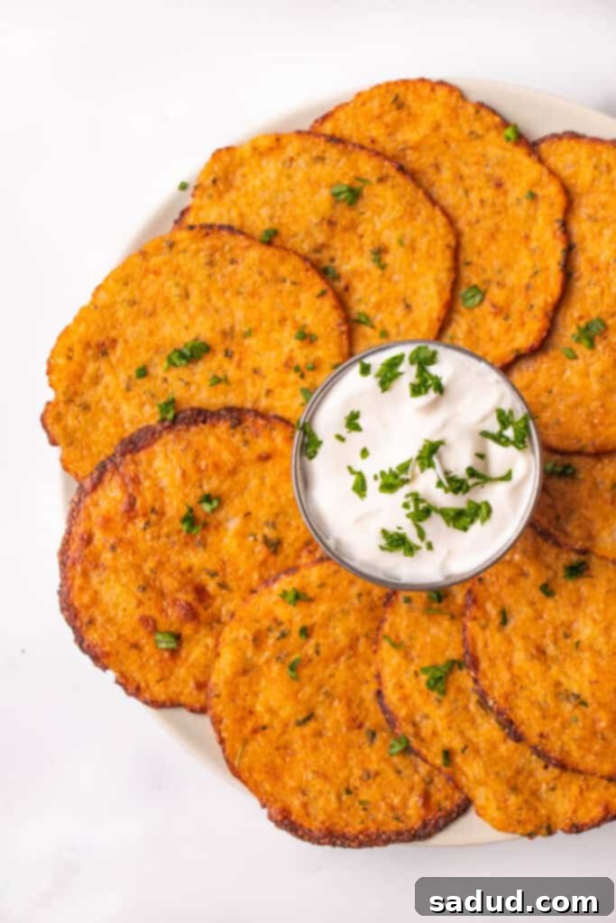 A circle of golden brown cauliflower chips surrounding a cup full of creamy sour cream dip, inviting a healthy and delicious snack experience.