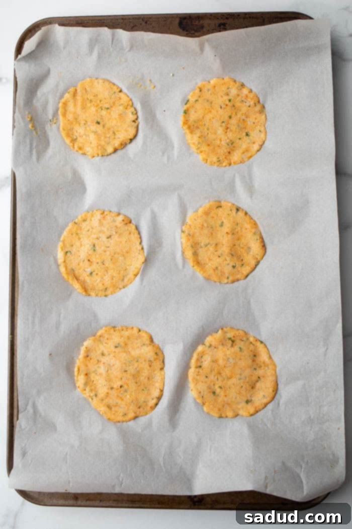 Shaping cauliflower dough into flat chips and arranging them on a baking sheet before baking until golden brown and crispy.