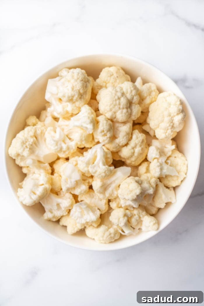 Cauliflower florets on a baking sheet, ready for steaming, with the oven preheated.